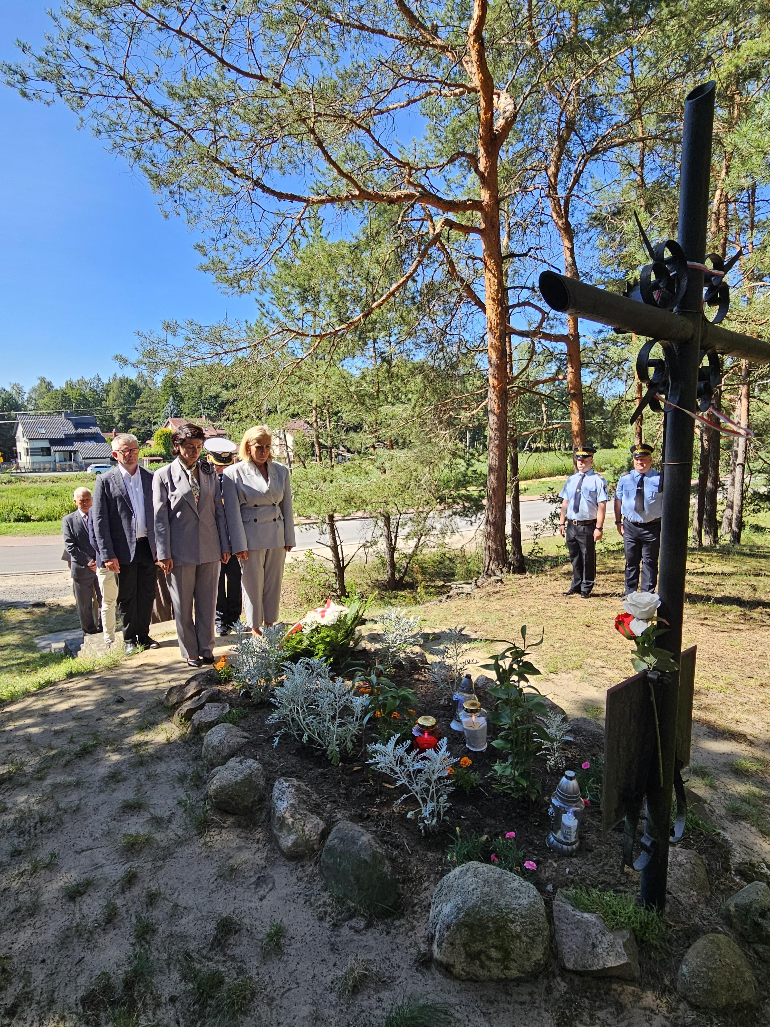 zdjęcie osób przy grobie, składające kwiaty